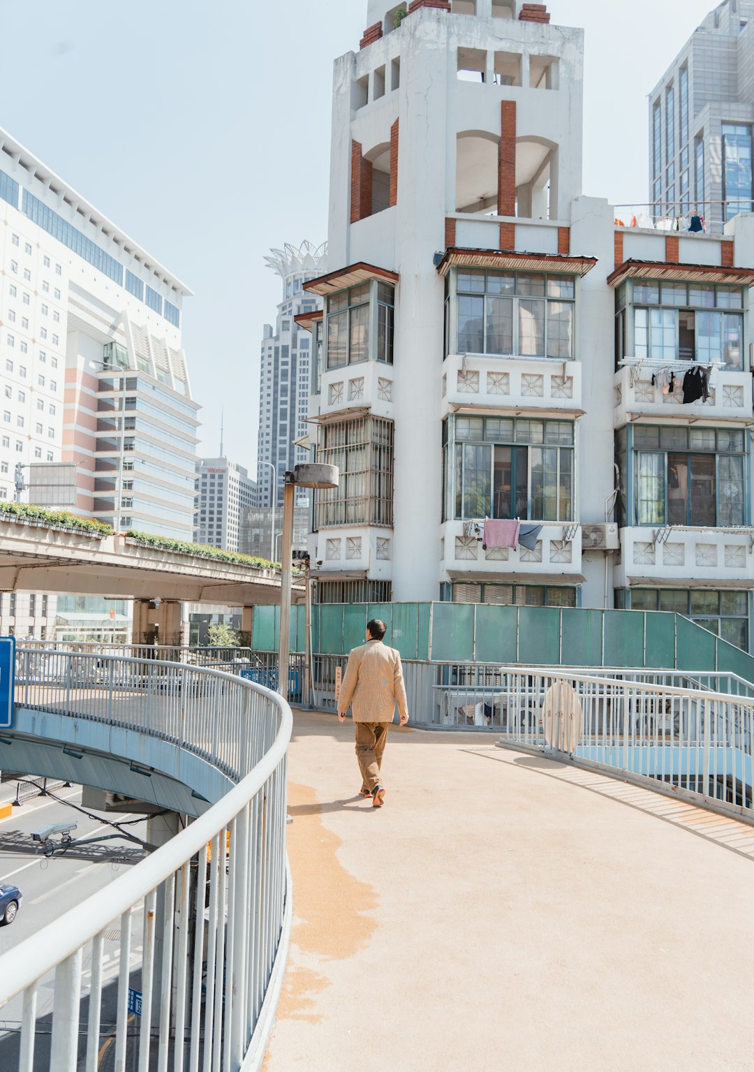 Photo by Evgeny Matveev A person walks on a bridge near buildings.